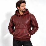 Man wearing the Crimson Forge Burgundy Leather Hoodie with a textured finish, drawstring hood, kangaroo pocket, and ribbed trims.