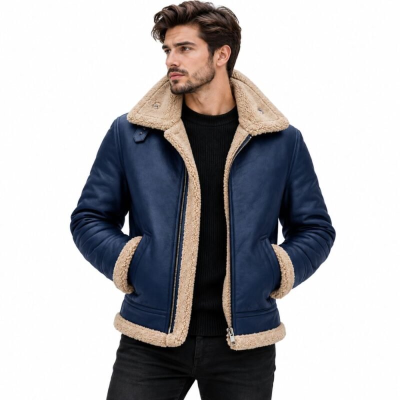 Man wearing a navy blue shearling leather jacket with a cream shearling collar, cuffs, hem, front zipper, and black knit sweater against a white background.