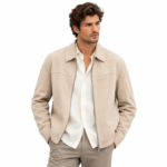 Man wearing a light beige suede jacket with pointed collar, front zipper, and clean panel stitching